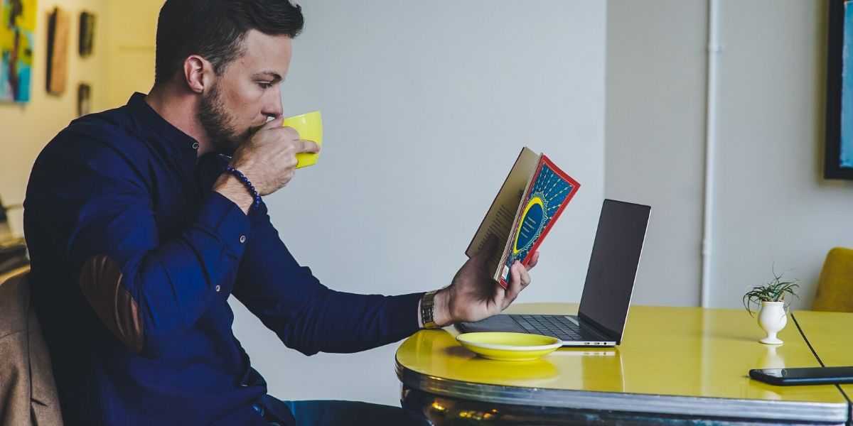 man-reading-book-while-drinking-coffee